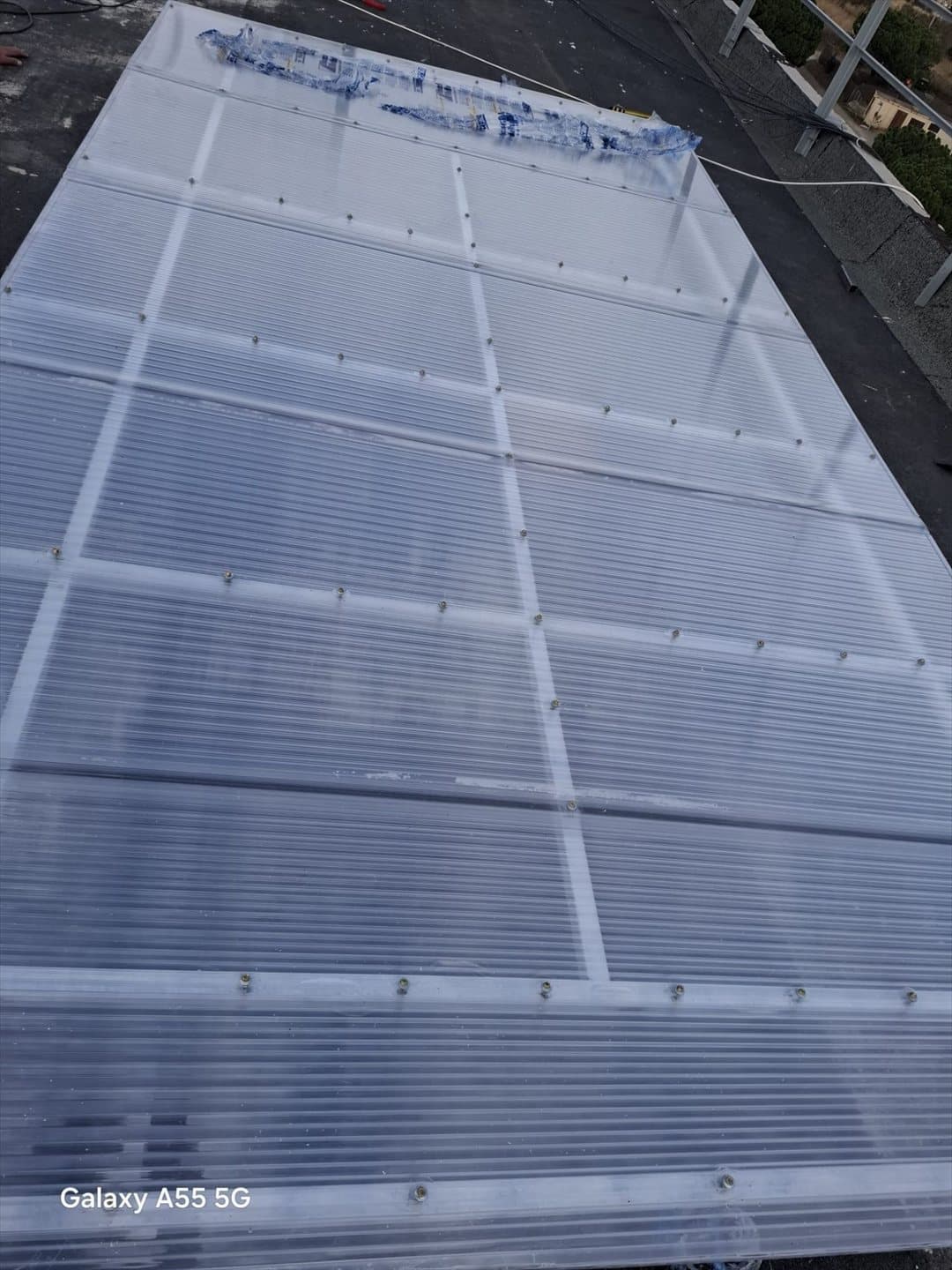 Tejadillo de policarbonato terminado sobre estructura metálica, protegiendo la zona de la intemperie.